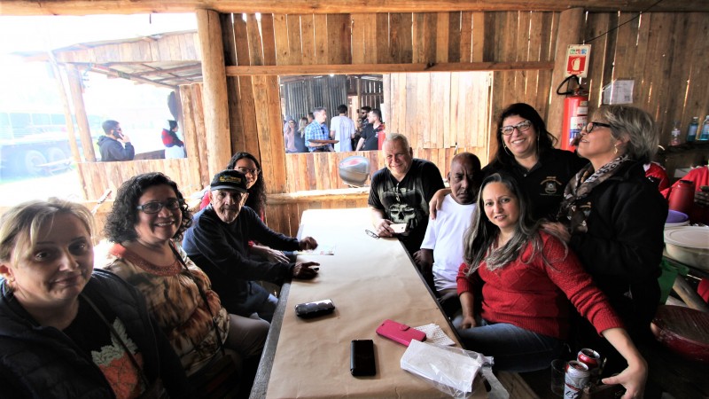 Sentados à mesa, dois ex-moradores do Hospital São Pedro aguardam o almoço junto à equipe multiprofissional que os acompanha